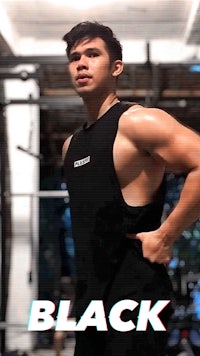 a man in a black tank top posing in a gym